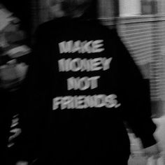 black and white photograph of man walking down the street wearing a sweatshirt with words written on it