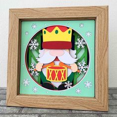 an ornament in a wooden frame with snowflakes around it and a crown on top