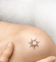 a woman's stomach with a small sun tattoo on her left side breast area