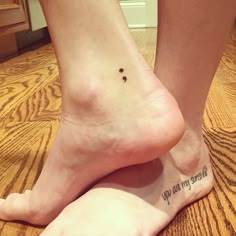 two people standing on the floor with their feet up and one has a small tattoo