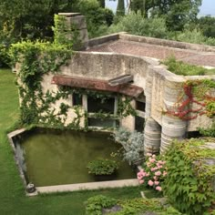 an aerial view of a building with water and plants in the foreground, surrounded by greenery