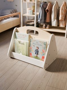 a child's book stand with books in it on the floor next to a bed