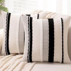 two black and white striped pillows sitting on top of a couch next to a window