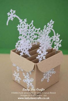 an open cardboard box with snowflakes in it on top of a brown table