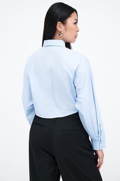 Our Ezra Shirt is a capsule wardrobe dream for your closet. Crafted from 100% crisp European poplin cotton, she offers a classic button-up silhouette in front, but with a cropped back for modern edge. Say hello, as well, to her diagonal seams at the front, sleek collar and long dolman sleeves finished with mother-of-pearl button cuffs. Wear Ezra tucked, tied or open and free—she never fails to inspire new looks.[SPLIT] Shannon, in light blue, is 5'8" (173 cm) tall, wearing a size M. Rocio, in li Elegant Cotton Cropped Shirt For Work, Classic Cropped Shirt For Office, Classic Cropped Shirt, Classic Cropped Shirt For Office In Spring, Classic Spring Cropped Shirt For Office, Elegant Cropped Cotton Shirt, Formal Button-up Poplin Tops, Formal Poplin Button-up Top, Classic Cropped Shirt With Button Cuffs