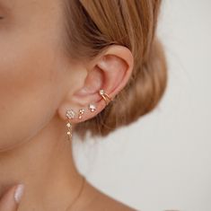 a close up of a woman's ear wearing gold earrings with flowers on them