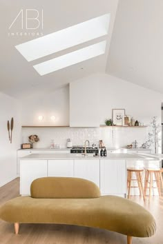 an open kitchen and living room area with white walls, wood flooring and skylights