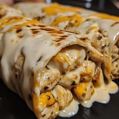 two burritos covered in cheese and chicken sitting on a plate