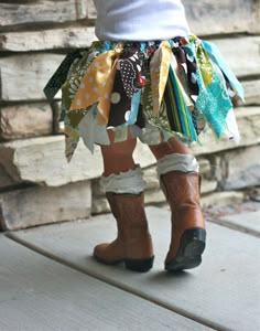 the legs of a child wearing cowboy boots are covered in colorful fabric and laces