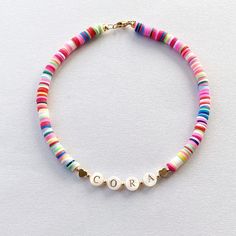 Add a burst of vibrant charm to your little one's outfit with our Bright Colorful Heishi Beads Name Necklace! This delightful piece combines the timeless elegance of mother of pearl gold name beads with an array of eye-catching, colorful hued beads. Each letter of your child's name is lovingly crafted with precision and adorned with a captivating spectrum of colors, creating a personalized gift that will surely bring smiles. These Heishi Name necklaces for toddlers and girls would also make great party favors for a Childs birthday party, Christmas gift, or Granddaughter gift. Beads are chosen randomly and the necklace is accented with 18K gold hearts and 18K round ball beads. Choose the length and number of name letters from the drop down menu and enter the name you would like in the perso Pearl Name, Beads Name, Toddler Necklace, Name Necklaces, Gold Hearts, Granddaughter Gift, Kids Necklace, Heishi Beads, Girls Necklaces