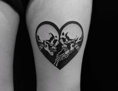 a woman's thigh with two skulls in the shape of a heart on it