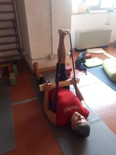 a man laying on the ground while holding onto an exercise band with one hand and another leg