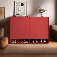 a red cabinet with several pairs of shoes on it in a living room next to a couch