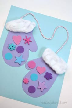 a pair of mitts made out of paper and felt are on a blue background