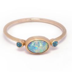 A captivating Australian boulder pipe opal with a vibrant overall aqua hue that displays gorgeous flashes of electric green and lilac.  Measuring 8.3 x 5.6 mm this 0.75 carat rainbow beauty is bezel set in 14k yellow gold with a sterling silver back. A duo of 2 mm faceted apatite gemstones add a playful pop of color an Oval Blue Opal Ring In 14k Gold, Laos Jewelry, Green And Periwinkle, Rainbow Beauty, Dream Future, Electric Green, Australian Boulder Opal, Stacking Bands, Opal Ring