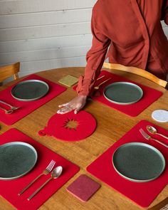 a person standing over a wooden table with plates and silverware on top of it