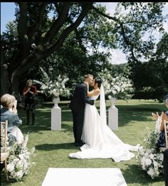 a bride and groom kissing in front of an outdoor ceremony