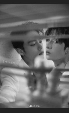 black and white photo of two people looking at each other through a glass window with their eyes closed