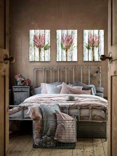 a bedroom with three paintings on the wall and a metal bed frame in front of it