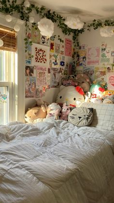 there are many stuffed animals on the wall above the bed in this room with white sheets