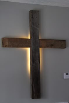 a wooden cross mounted to the side of a wall with two lights on each side