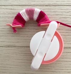 a pink and white object sitting on top of a wooden table next to a string