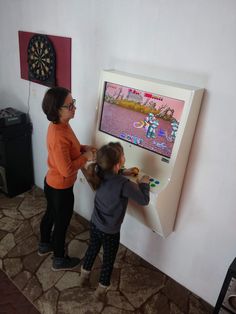 two young children playing video games on a wall mounted tv screen in a living room