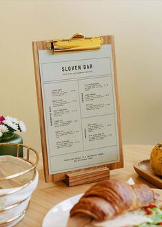 a wooden menu board sitting on top of a table next to a plate of food