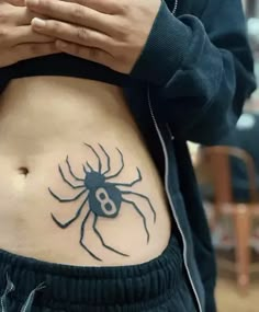 a woman's stomach with a spider tattoo on her belly and the number 8