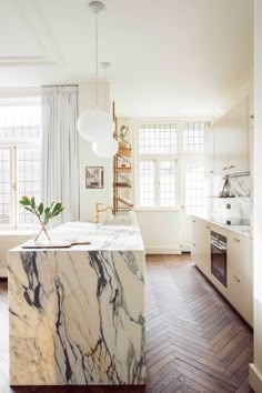 a kitchen with marble counter tops and white cabinets in the center, along with wood flooring