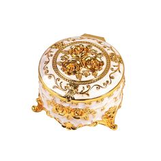 a white and gold decorated box on a white surface with golden decorations around the lid