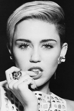 a black and white photo of a woman with her hand to her face, wearing earrings