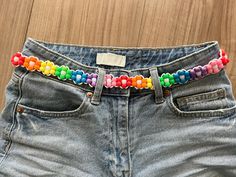 a pair of denim shorts with colorful beads on the waist and belt attached to them