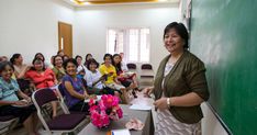 a woman standing in front of a classroom full of people