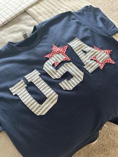 a t - shirt that has the number fifteen on it and is decorated with red, white and blue stars