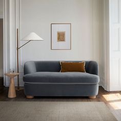 a living room with a blue couch and lamp on the side table in front of it