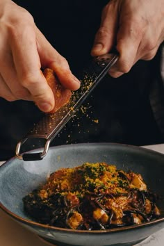 a person is sprinkling seasoning on food in a bowl