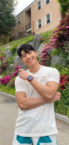 a man standing in front of a building with his arm around his chest and smiling