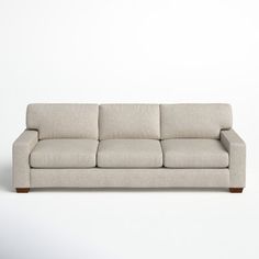 a white couch sitting on top of a wooden floor next to a wall with a light colored background