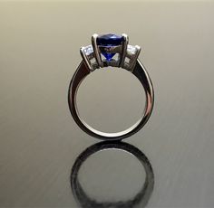 Dekara Designs Collection Metal- 90% Platinum, 10% Iridium. Stones- 1 Natural Untreated 3.88 Carat Oval Cut Ceylon Blue Sapphire. 2 Moon Cut Diamonds, F-G Color VS1 Clarity 0.77 total carats This ring is a size 6, but could be sized up or down a few sizes. This ring could be made in your specific size within 5-10 business days. Could take a little more time due to the ceylon sapphire being a rare stone. The sapphire may be a bit smaller or bigger. We can make the same design in a smaller or bigg Blue Tanzanite Ring With Trillion Cut, Formal Blue Sapphire Ring Gia Certified, Blue Sapphire Three-stone Promise Ring, Blue Three Stone Sapphire Promise Ring, Trillion Cut Tanzanite Rings For Wedding, Trillion Cut Blue Sapphire Ring For Gift, Blue Sapphire Ring With Trillion Cut Diamond, Blue Trillion Cut Sapphire Ring With Prong Setting, Trillion Cut Blue Sapphire Ring With Diamond