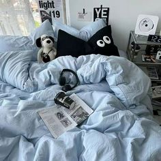 a teddy bear sitting on top of a blue comforter in a bed with headphones