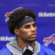 a man with a headband on speaking into a microphone