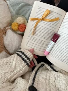 a person laying in bed reading a book with a yellow ribbon on it and some food