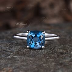 a blue diamond ring sitting on top of a rock