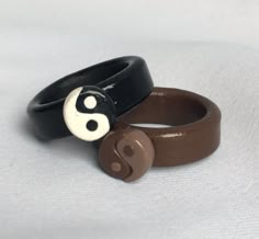 two black and brown bracelets with white yin - yang symbols on them, sitting next to each other