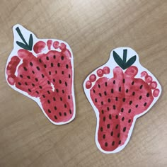 two paper strawberries cut out to look like they are painted