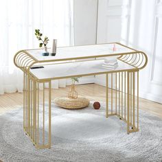 a table with a glass top and gold metal frame, on a rug in front of a window