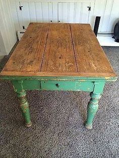 an old wooden table with green paint on the top and legs, in front of a white