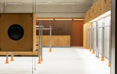 an empty room with several speakers in the center and orange poles on the wall behind it