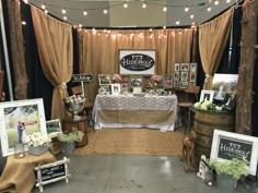 a table with pictures and photos on it in front of a curtained area that has lights strung from the ceiling